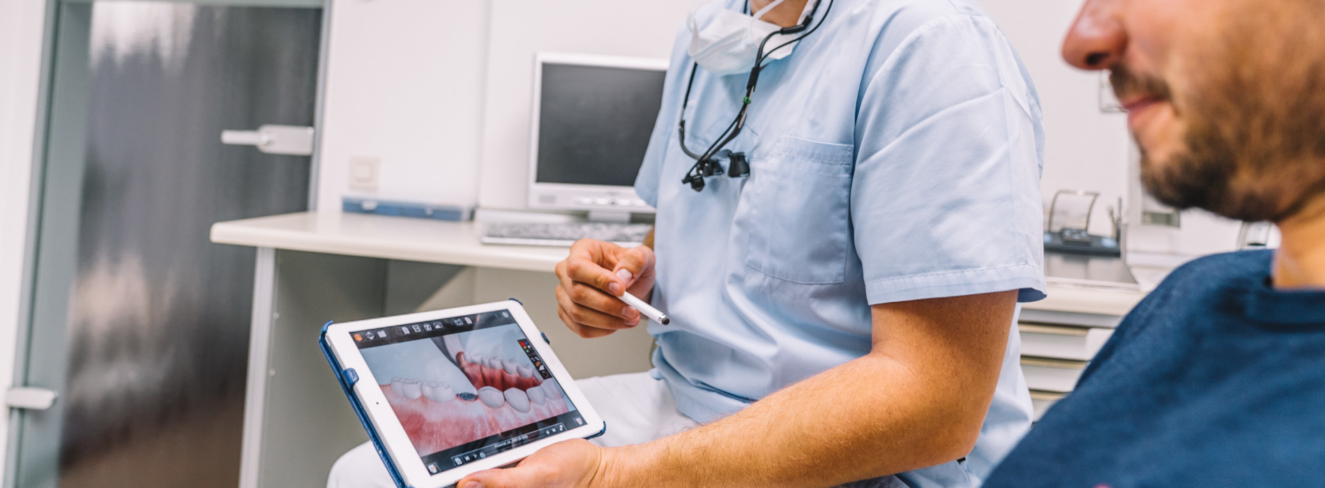 Zahnarzt erklärt einem Patienten eine Aufnahme auf dem Tablet